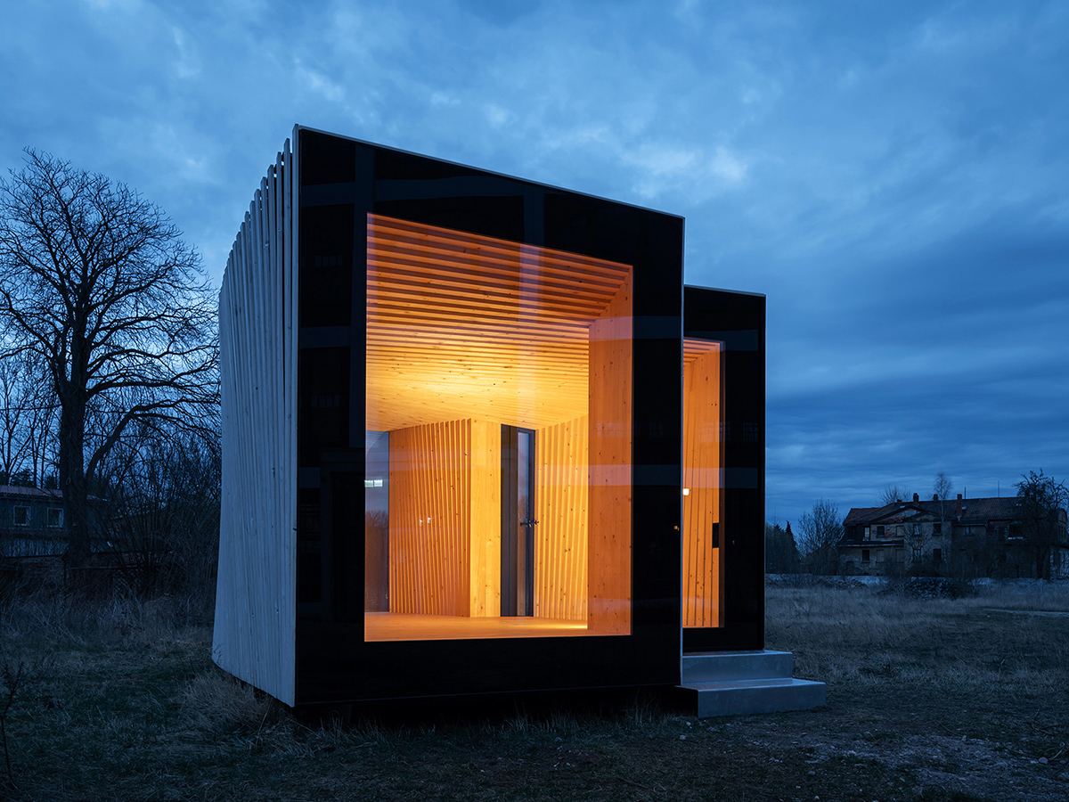 IBA Timber Prototype House: Timber prototype house at dusk with lit windows