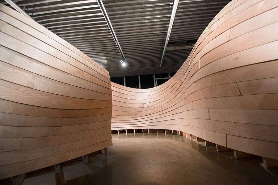 Robot-Assisted Assembly in Wood Construction: Stacked timber walls curving through a hall